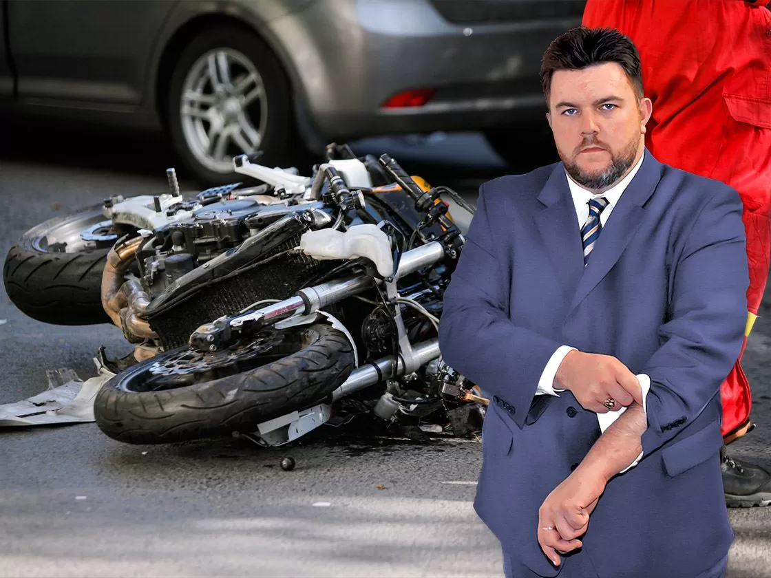 Ron Sholes, Jacksonville motorcycle accident lawyer, standing by a damaged motorcycle.