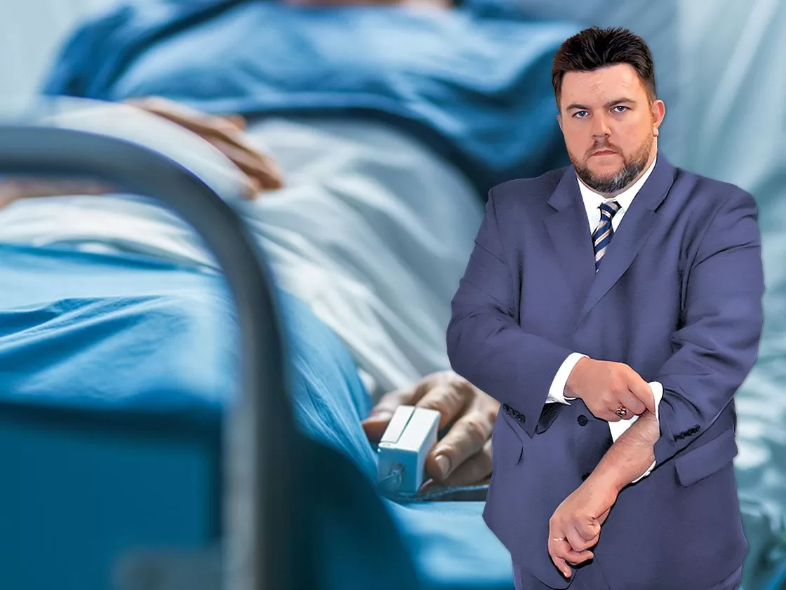 Ron Sholes, Jacksonville PIP injury lawyer, visiting a client in a hospital bed after an auto accident.