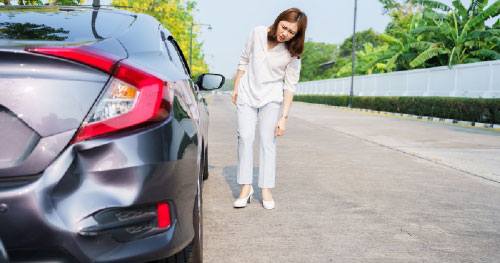 Stock image of a woman standing outside a store, noticing damage to her car from a hit-and-run accident, symbolizing Ron Sholes, P.A.'s expertise in handling hit-and-run claims