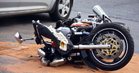 Stock image of a motorcycle on its side after an accident, with a rider standing nearby looking at the damage. This image represents the dangers motorcyclists face on the road and the need for legal representation in motorcycle accident cases. Ron Sholes, P.A. advocates for motorcycle accident victims, ensuring they receive the justice they deserve